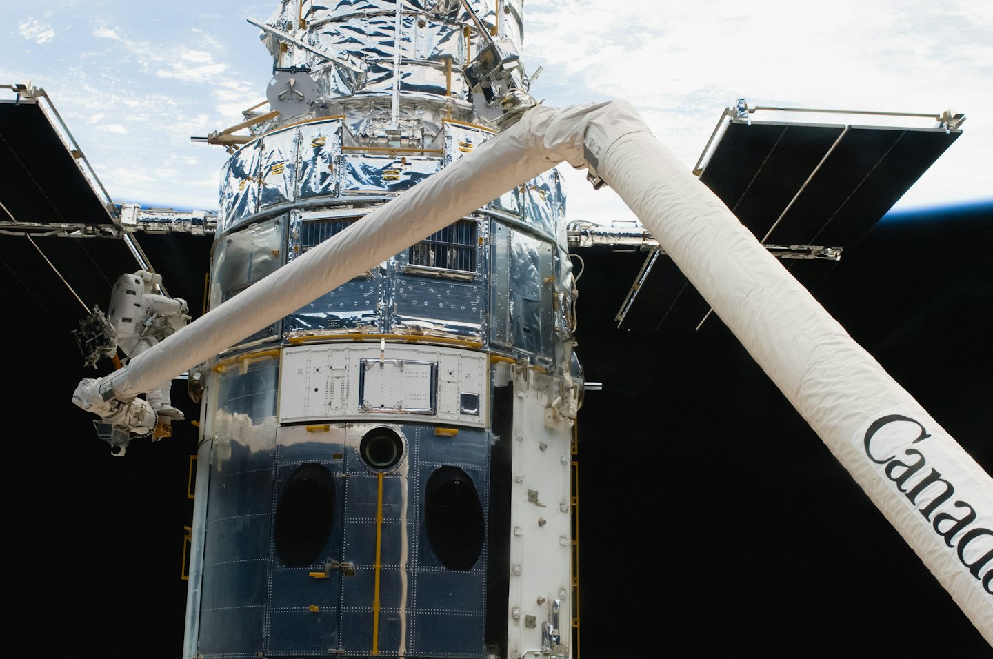 An astronaut works on the Hubble Space Telescope in orbit.