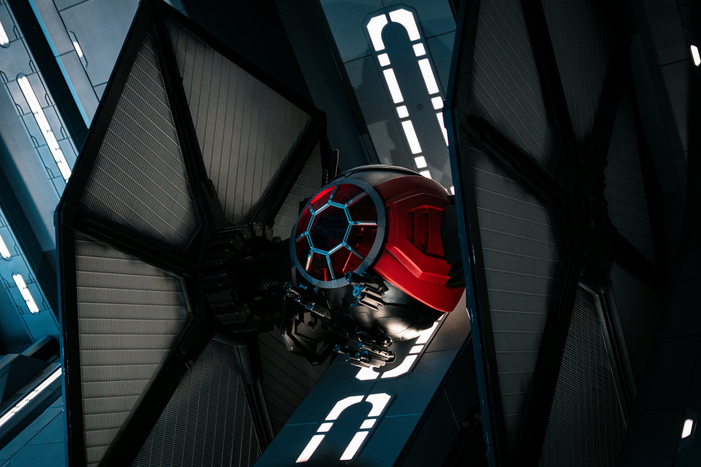Futuristic red and black spaceship parked in a dark hangar.