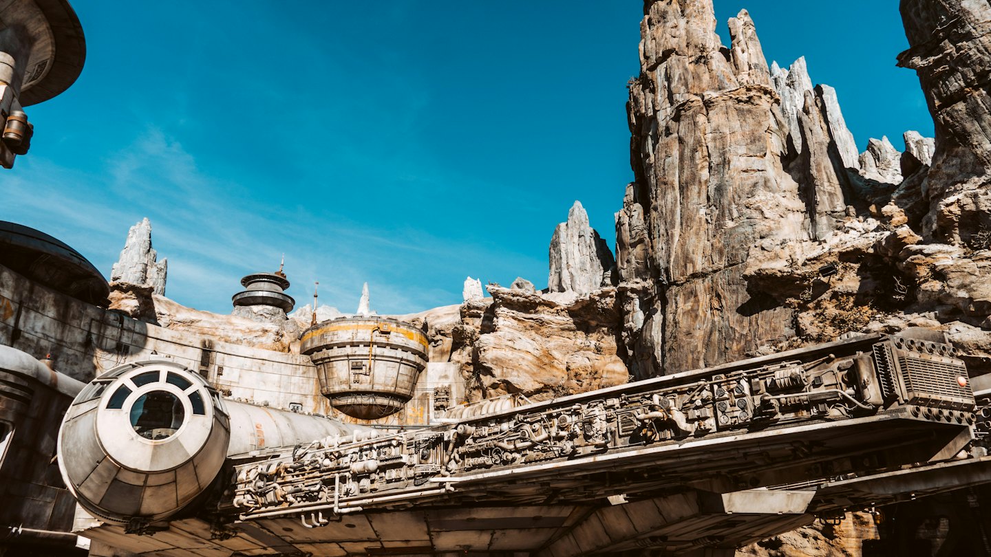 Sci-fi spaceship docked among rugged rock formations and futuristic buildings.