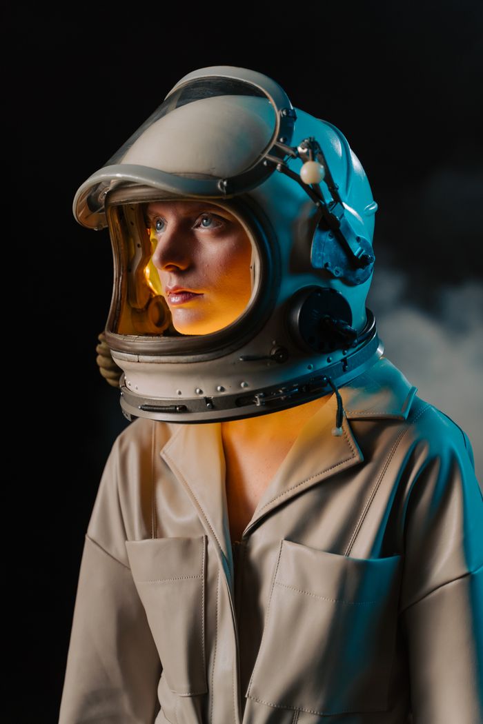 A captivating portrait of a woman wearing a space helmet with a neon glow against a dark background.